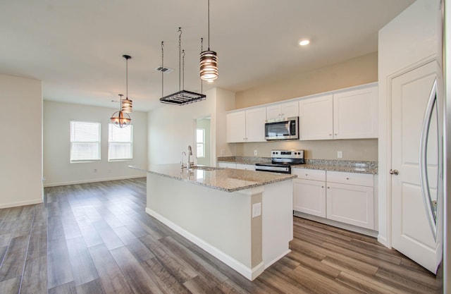 kitchen featuring a center island with sink, appliances with stainless steel finishes, hanging light fixtures, sink, and white cabinetry