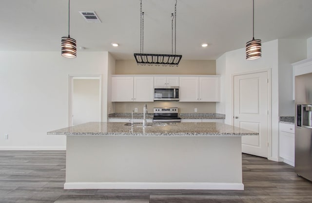 kitchen with decorative light fixtures, an island with sink, appliances with stainless steel finishes, and white cabinetry