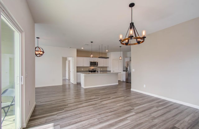 unfurnished living room with sink, light hardwood / wood-style flooring, and a chandelier