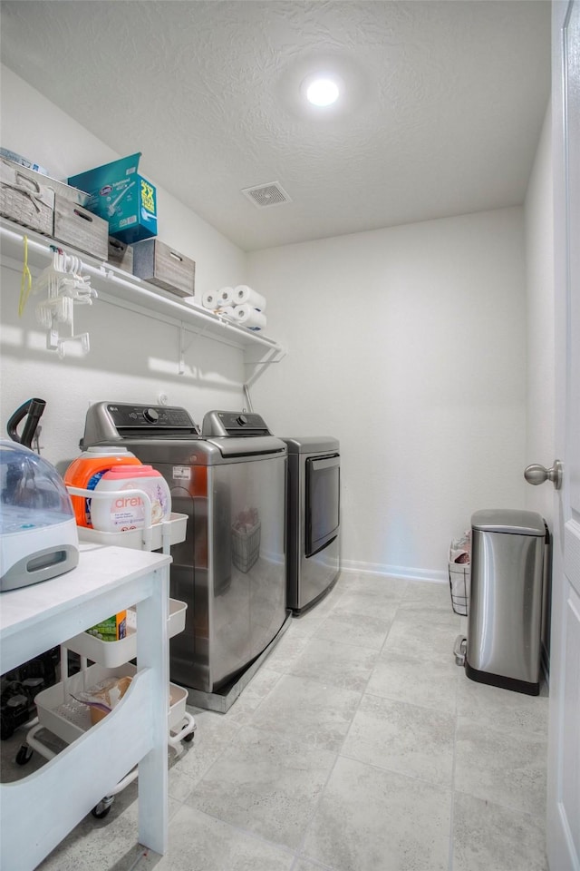 washroom with washing machine and dryer and a textured ceiling