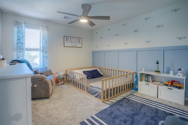 bedroom with light colored carpet, ceiling fan, and a crib