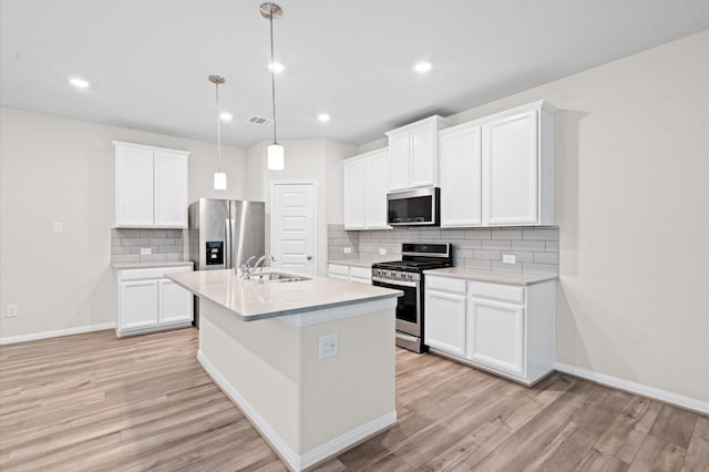 kitchen with stainless steel appliances, decorative light fixtures, white cabinetry, and sink