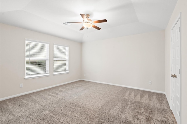 carpeted spare room with a raised ceiling and ceiling fan