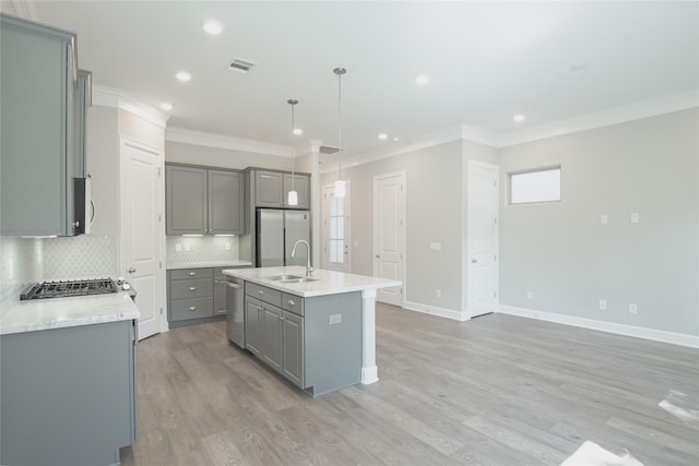 kitchen with stainless steel appliances, sink, an island with sink, gray cabinets, and pendant lighting