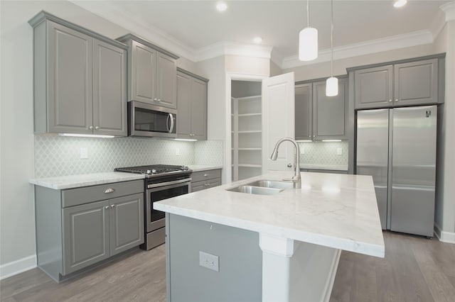 kitchen with sink, stainless steel appliances, light stone countertops, and a center island with sink