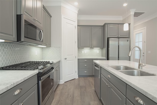 kitchen featuring appliances with stainless steel finishes, backsplash, gray cabinetry, and sink