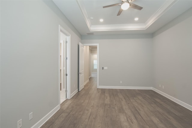 spare room featuring ceiling fan, dark wood-type flooring, ornamental molding, and a raised ceiling