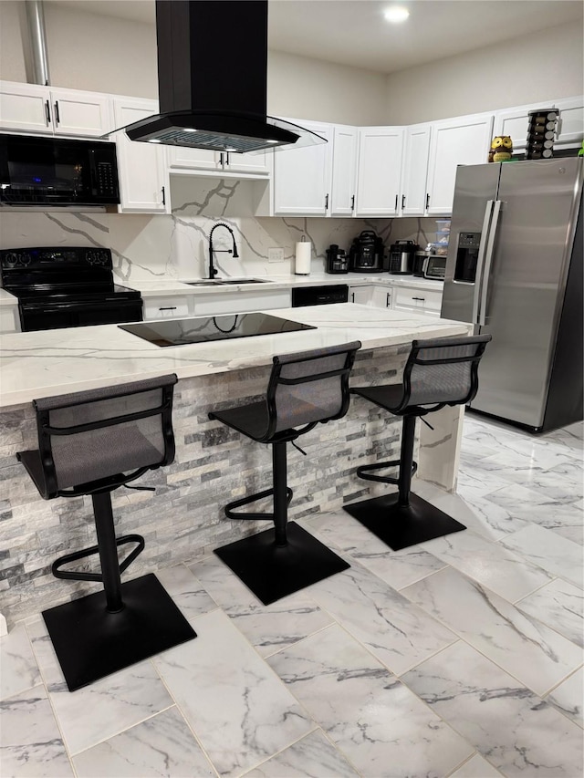 kitchen with sink, white cabinetry, a breakfast bar, island range hood, and black appliances