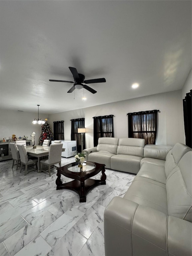 living room featuring ceiling fan with notable chandelier