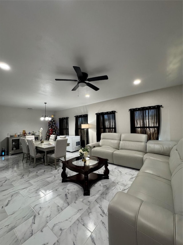 living room featuring ceiling fan with notable chandelier