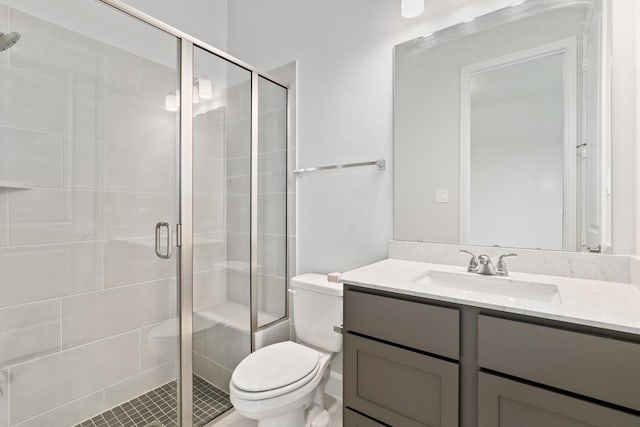 bathroom featuring toilet, a shower with door, and vanity