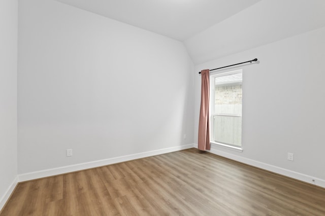 spare room with light hardwood / wood-style flooring and vaulted ceiling