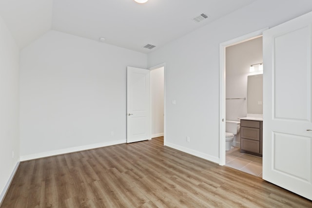 unfurnished bedroom featuring ensuite bath and light hardwood / wood-style flooring