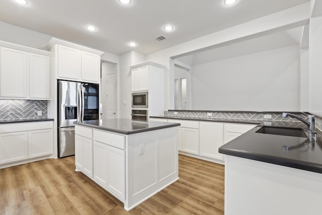 kitchen featuring appliances with stainless steel finishes, tasteful backsplash, white cabinetry, and sink