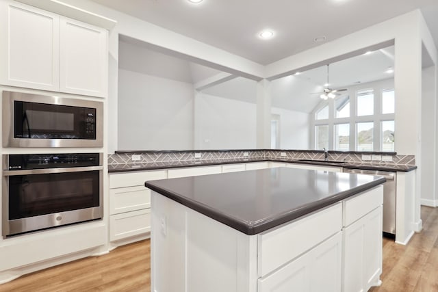 kitchen with appliances with stainless steel finishes, light wood-type flooring, a center island, ceiling fan, and white cabinets