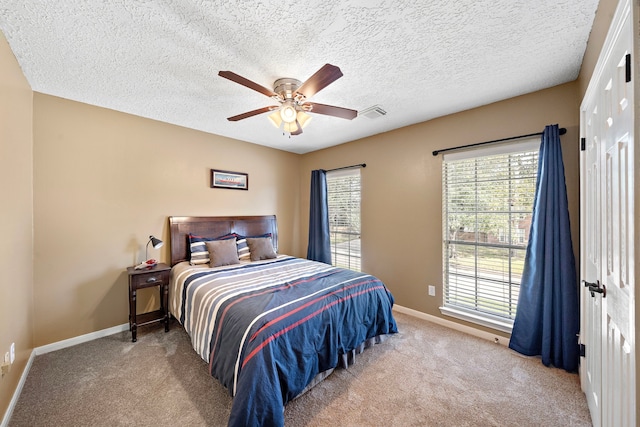 bedroom with a textured ceiling, ceiling fan, and light colored carpet