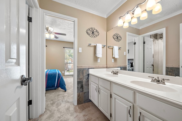 bathroom with crown molding, vanity, ceiling fan, tile walls, and a textured ceiling