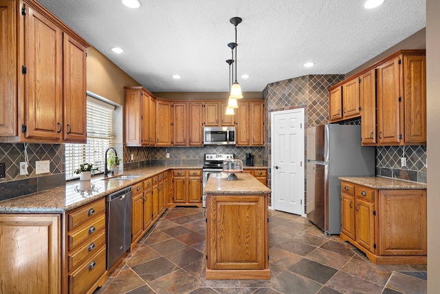 kitchen featuring appliances with stainless steel finishes, light stone countertops, pendant lighting, a kitchen island, and sink