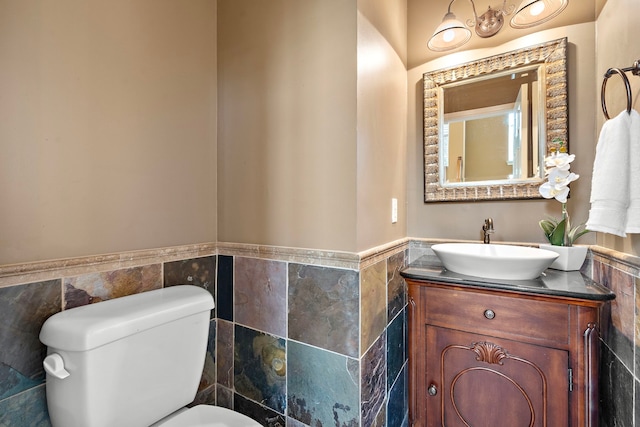 bathroom featuring toilet, vanity, and tile walls