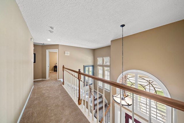 corridor with a textured ceiling and carpet floors