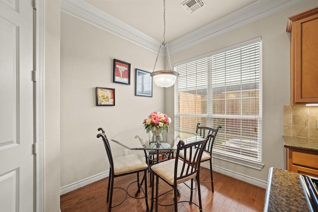 dining space with ornamental molding and light hardwood / wood-style flooring