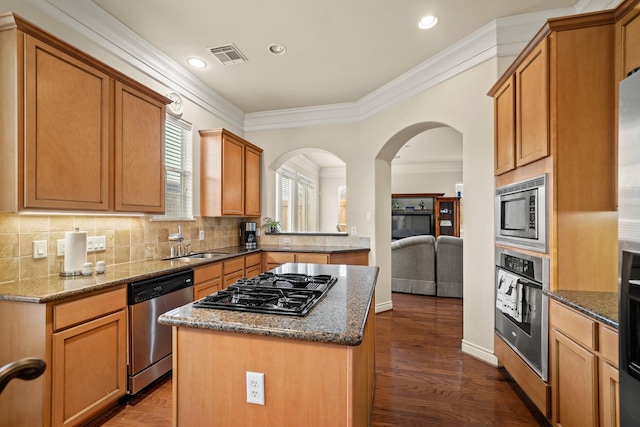 kitchen with stainless steel appliances, dark stone countertops, dark hardwood / wood-style floors, and a center island