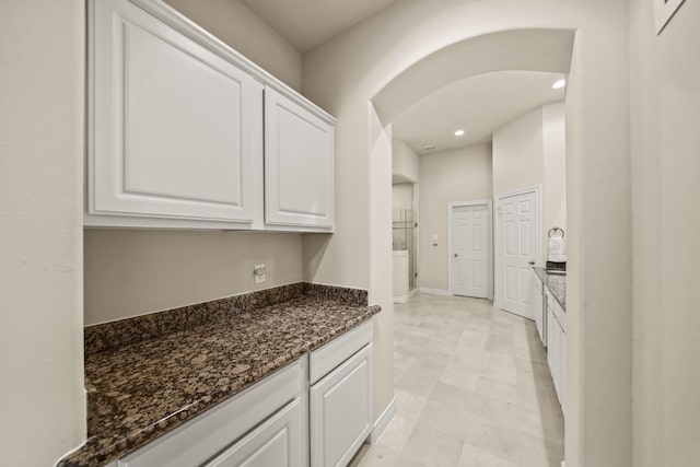 kitchen with dark stone counters and white cabinetry