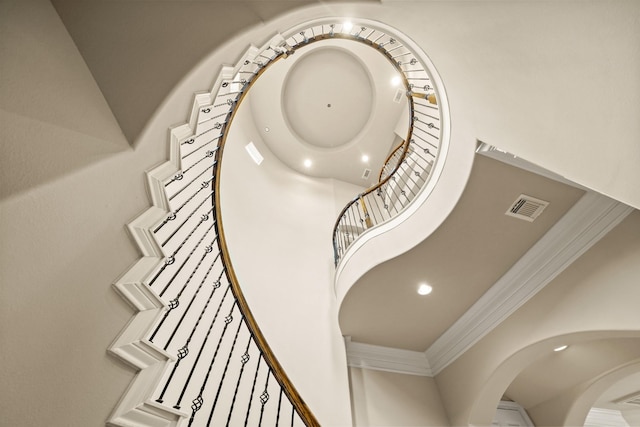 stairs with ornamental molding and a towering ceiling