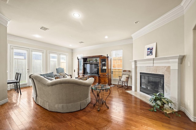 living room featuring a premium fireplace, hardwood / wood-style flooring, and crown molding