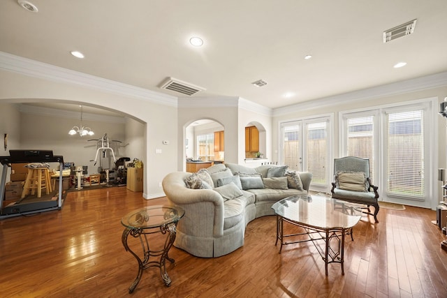 living room featuring an inviting chandelier, ornamental molding, and hardwood / wood-style flooring