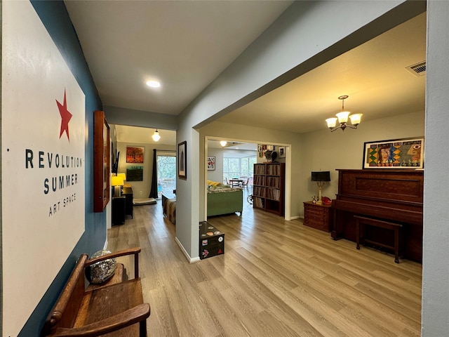 hallway featuring light hardwood / wood-style flooring and a chandelier