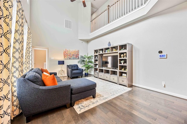 living room featuring a towering ceiling, ceiling fan, and hardwood / wood-style floors