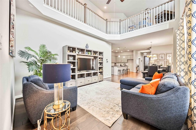 living room with ceiling fan, a towering ceiling, and wood-type flooring