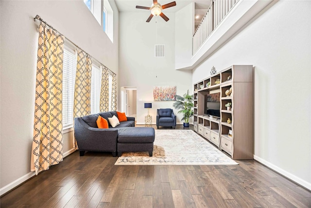 living room featuring a high ceiling, ceiling fan, and dark hardwood / wood-style floors