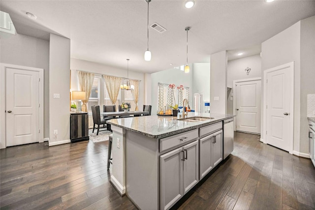 kitchen with sink, dishwasher, light stone counters, an island with sink, and pendant lighting