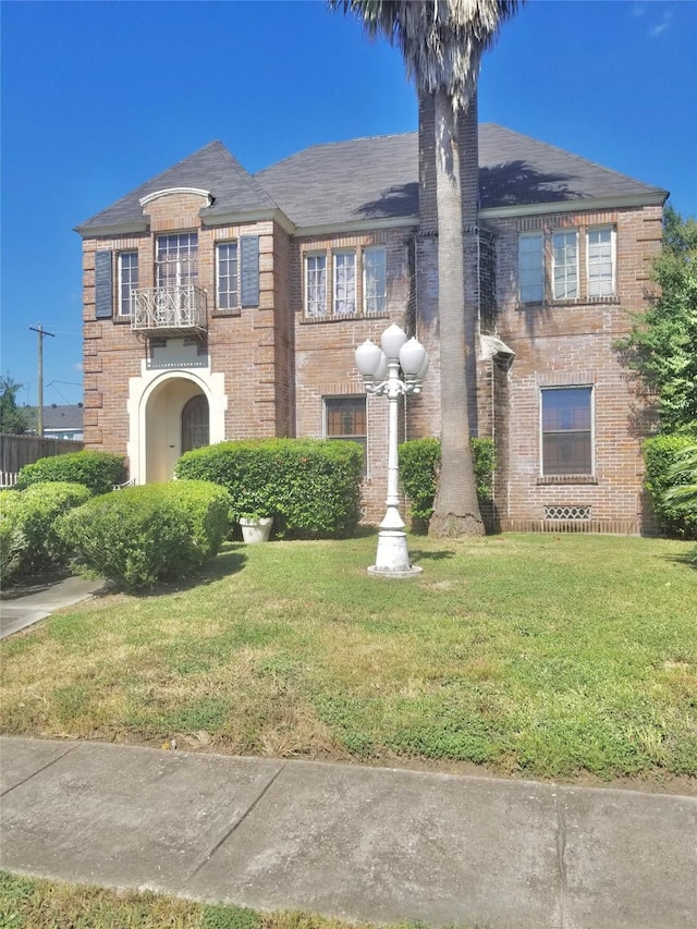 view of front facade with a balcony and a front lawn