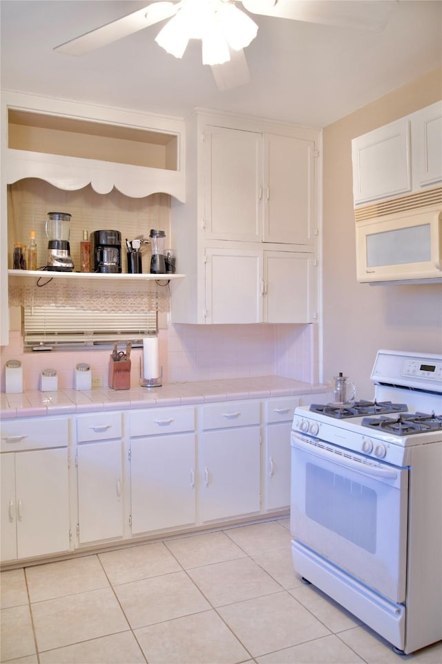 kitchen with white appliances, ceiling fan, white cabinetry, and tile counters