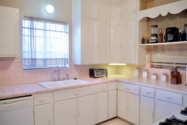 kitchen with white dishwasher, tile countertops, sink, white cabinets, and tasteful backsplash