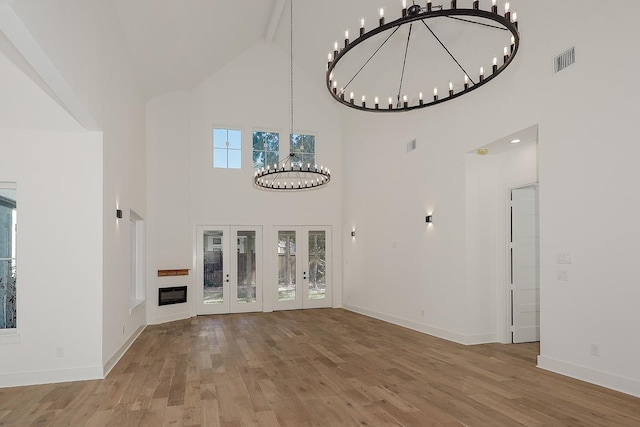 unfurnished living room featuring high vaulted ceiling, beam ceiling, french doors, and wood-type flooring