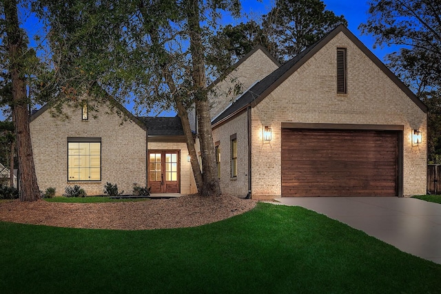 view of front of home with a garage, french doors, and a front lawn