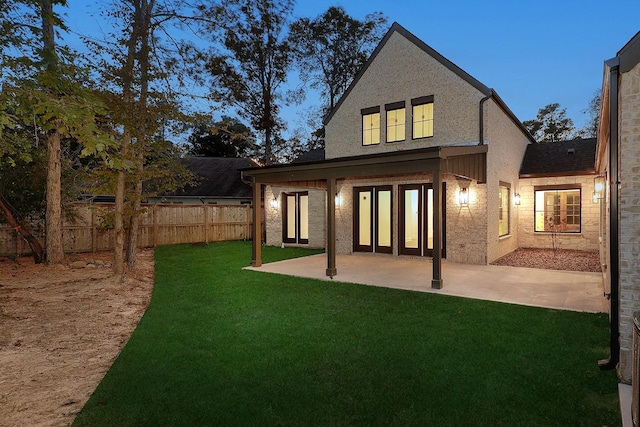 back house at dusk with a yard and a patio area