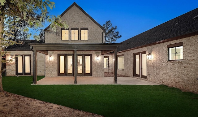 rear view of house with a lawn, french doors, and a patio