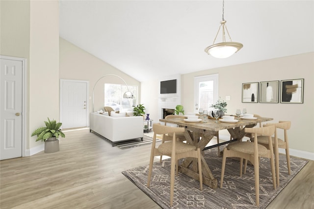 dining space featuring high vaulted ceiling and light hardwood / wood-style floors