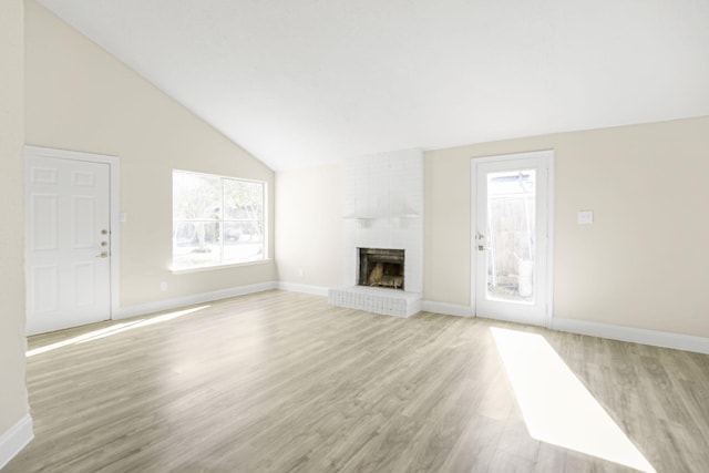 unfurnished living room with a brick fireplace, high vaulted ceiling, and light hardwood / wood-style flooring