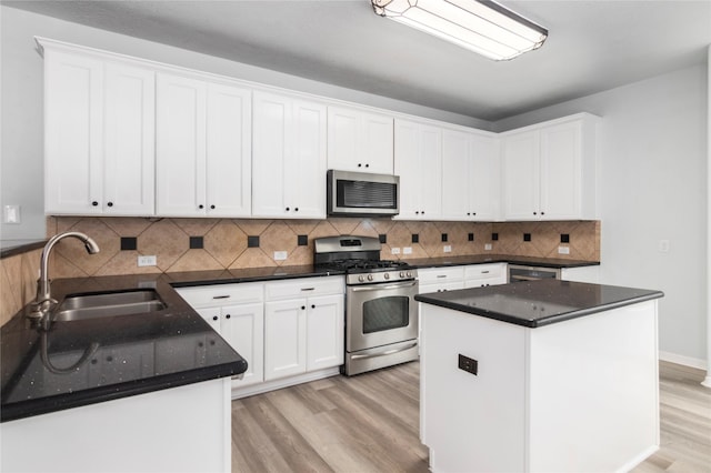 kitchen with sink, appliances with stainless steel finishes, light hardwood / wood-style flooring, and white cabinetry