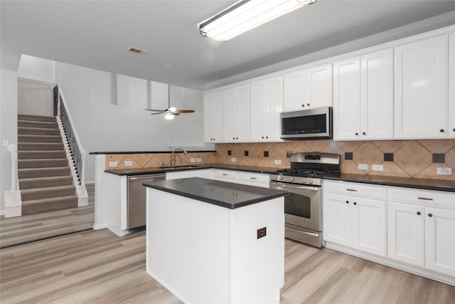 kitchen featuring ceiling fan, stainless steel appliances, white cabinetry, and a kitchen island