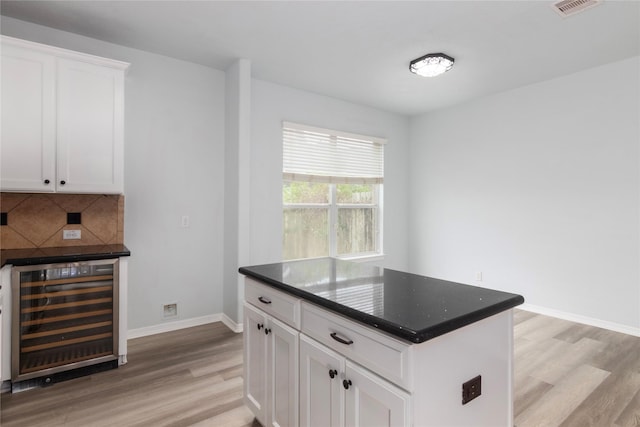 kitchen with white cabinets, light hardwood / wood-style flooring, backsplash, and wine cooler