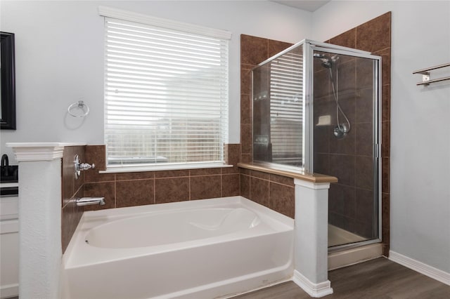 bathroom featuring plus walk in shower, wood-type flooring, and plenty of natural light