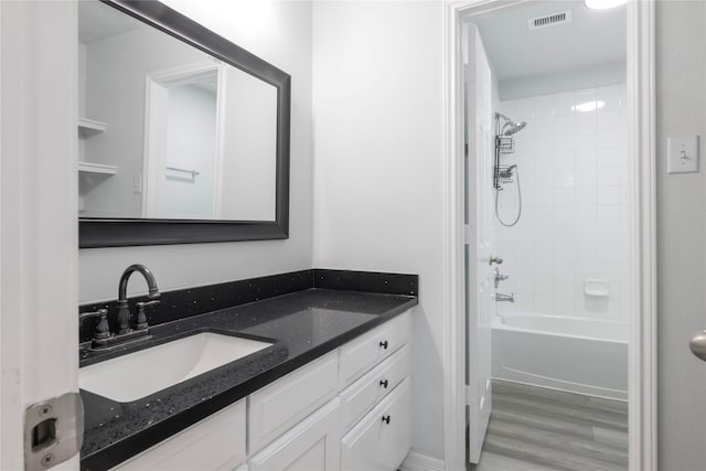 bathroom with tiled shower / bath combo, hardwood / wood-style flooring, and vanity