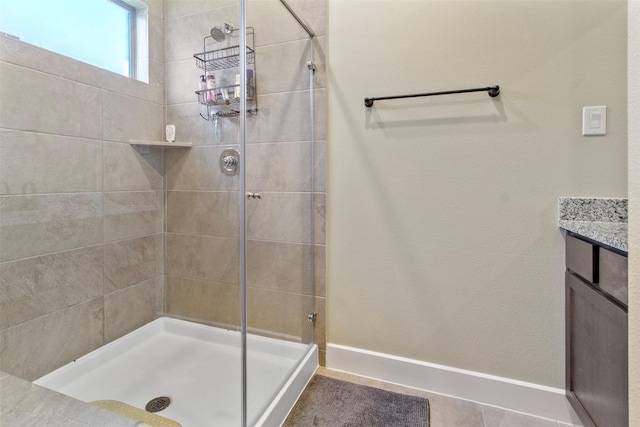 bathroom with a shower with door, vanity, and tile patterned floors